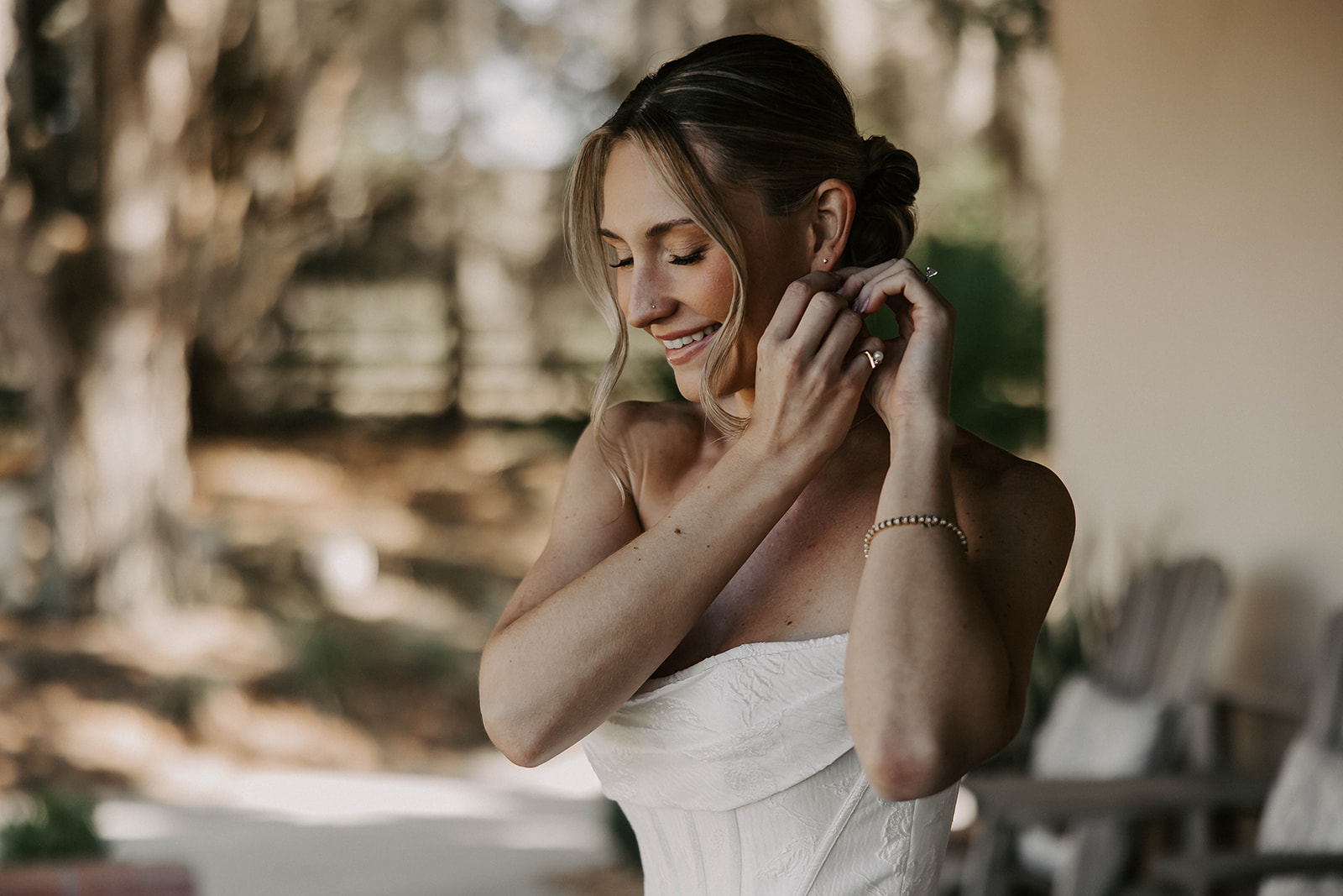 bride getting ready earrings la hacienda brooksville florida - A Fall Wedding at La Hacienda on Snow Hill in Brooksville, FL Smiling bride in a strapless white wedding gown putting on earrings while getting ready at La Hacienda on Snow Hill wedding venue in Brooksville Florida near Tampa