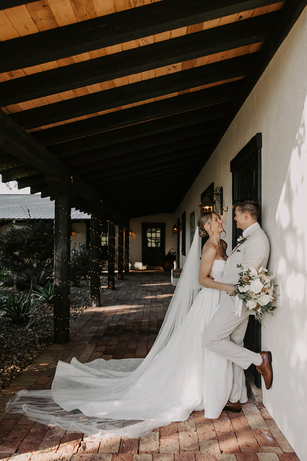 bride groom portrait la hacienda snow hill brooksville - A Fall Wedding at La Hacienda on Snow Hill in Brooksville, FL Bride and groom share a joyful moment on the brick-paved veranda at La Hacienda on Snow Hill wedding venue in Brooksville Florida, bride wearing a strapless gown with cathedral veil and holding a white and blush bouquet