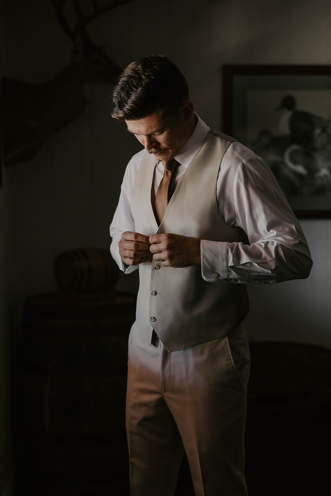 groom getting ready la hacienda snow hill brooksville - A Fall Wedding at La Hacienda on Snow Hill in Brooksville, FL Groom buttoning his ivory vest while getting ready at La Hacienda on Snow Hill wedding venue in Brooksville Florida