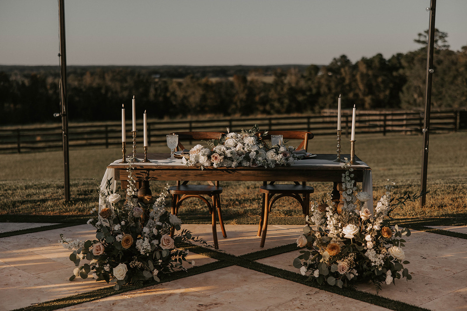 sweetheart table floral setup la hacienda snow hill - A Fall Wedding at La Hacienda on Snow Hill in Brooksville, FL Elegant outdoor sweetheart table with lush white and blush floral arrangements, taper candles, and rustic wood furniture at La Hacienda on Snow Hill wedding venue in Brooksville Florida