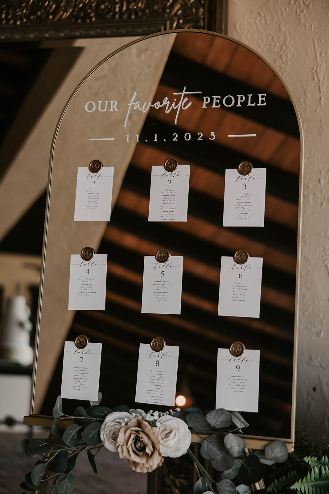 wedding seating chart mirror sign la hacienda brooksville - A Fall Wedding at La Hacienda on Snow Hill in Brooksville, FL Elegant arched mirror seating chart display reading Our Favorite People dated 11.1.2025 with nine table cards secured by gold wax seals and white floral arrangement at La Hacienda on Snow Hill wedding venue in Brooksville Florida