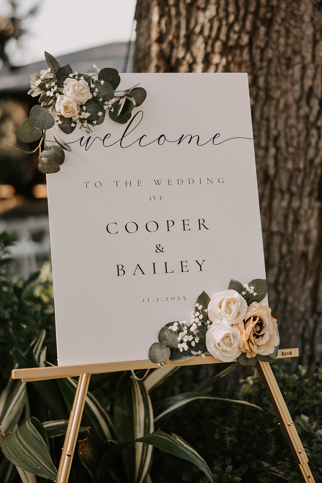 wedding welcome sign cooper bailey la hacienda brooksville - A Fall Wedding at La Hacienda on Snow Hill in Brooksville, FL Elegant wedding welcome sign for Cooper and Bailey dated November 1 2025 decorated with cream roses and eucalyptus on a gold easel at La Hacienda on Snow Hill in Brooksville Florida